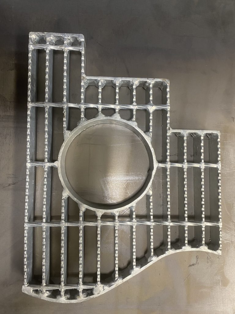 Finesse and strange shaped model of grate steel panel represents our technological advantages of grated steel improvements. The top portion of the model panel features steps with antivibration banding applied even to area in close proximity to cross bar. The bottom portion of the model ends with intense waved banding that is welded to each cross bar. The circular opening features inside banding also fully welded with antivibration welds. JW Investrade Inc. for metalgrating.ca 2023, London, Ontario