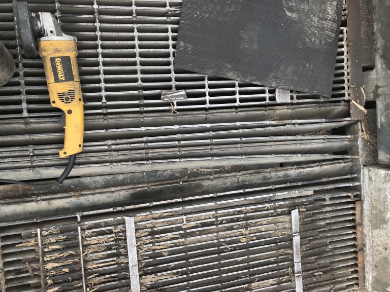 Large section of welded bar metal grates is heavily damaged. This panel should be replaced since it has 13 broken off bearing bars from banding and has multiple missing cross bars. However, we have to fix it since the client does not have the spare panel. JW Investrade Inc. for metalgrating.ca 2018, Strathroy, Ontario