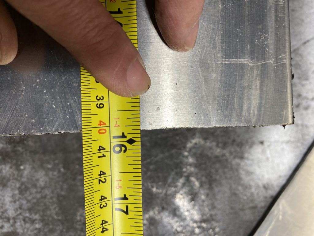 By pressing down on the edge of measuring tape on imperial side I have closed the distance between the edge of tape and the surface of material for grater measurement accuracy. With a finger I have pressed down on the edge of the tape measure on the imperial side and the reading is 15 inches and 13/16. JW Investrade Inc for metalgrating.ca 2023 London, Ontario