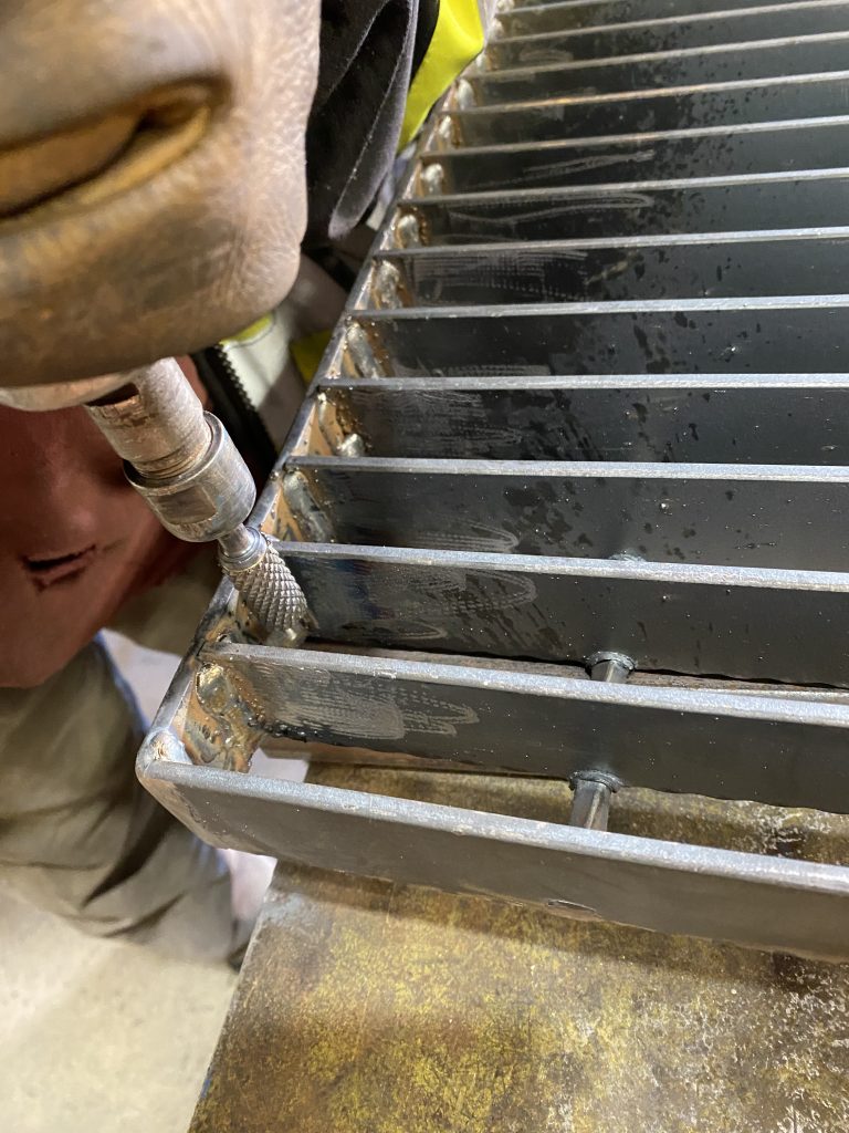 The grated steel must be free of spatter according to NAAMM standard therefore we clean the welding spatter between the bearing bars with pencil grinder. JW Investrade Inc. for metalgrating.ca 2023, London Ontario