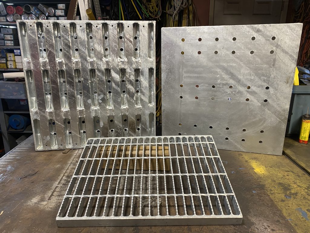 3 hot galvanized custom drain covers hat visualize customization of drain covers, ranging from size, acceptable dynamic and static loads, and way of installation. The left one is a supported style drain cover vehicular traffic with holes in 1/2" steel plate and mixed steel plate support consisting with heavy steel flats and HSTS. The drain cover to the right is a unsupported style cover with very similar characteristic to the first cover. The drain cover in the middle is a supported style drain cover for pedestrians featuring serrated bar grating and heavy banding with heavy antivibration welds. For JW Investrade Inc. www.metalgrating.ca, London, Ontario, 2024