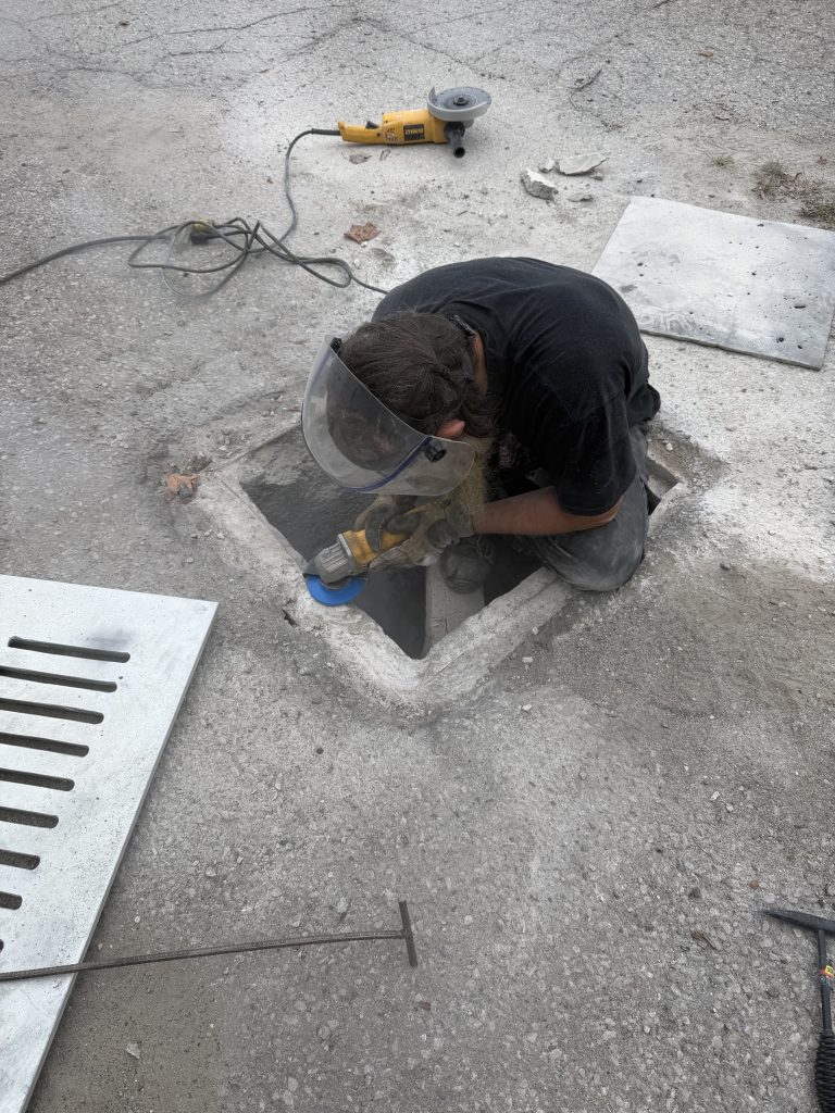 Worker is grinding with the grinder the edges of the basin to form the step down of the edge for sunk in effect of unsupported lid. In this way the step down by itself will prohibit the horizontal movement of the lid. For JW Investrade Inc. www. metalgrating.ca. London, Ontario, 2026
