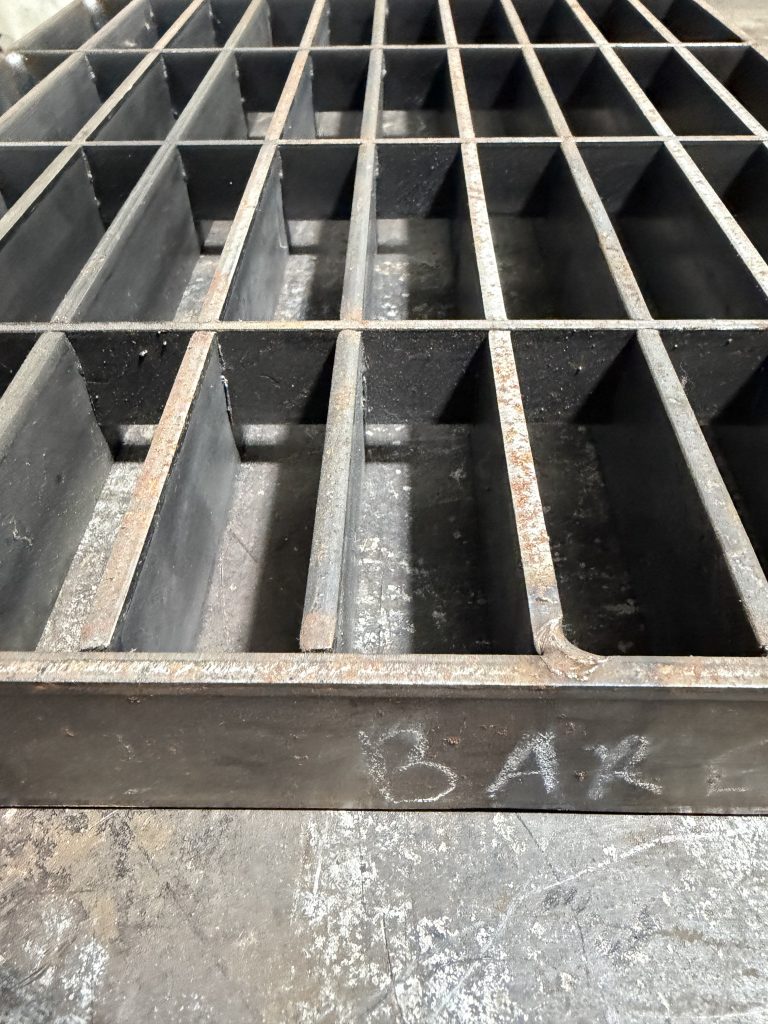 The cross bars that are perpendicular to load bearing bars stabilize the whole structure much deeper against the dynamic loads in comparison to crossbars in welded grating. Due to its high cost this grating is not popular on tranches and driveways. Additional need to weld crossbars on the outside of rim bars makes it more difficult for maintaining the gap between the panel and its steel support in trenches or driveways. JW Investrade Inc. for Metalgrating.ca, 2026, Lucan Ontario.
